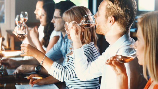 Group of people sitting at a bar tasting glasses of wine