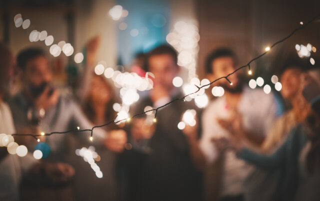 Group of people celebrating with sparklers under string lights
