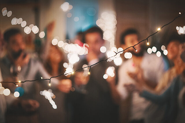 Group of people celebrating with sparklers under string lights