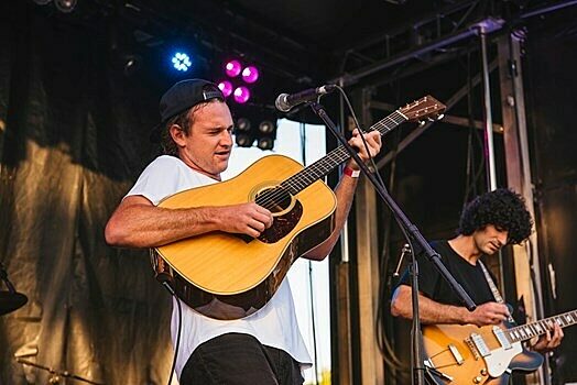 Two guitarists performing on stage at Darwin Ski Club under purple stage lighting.
