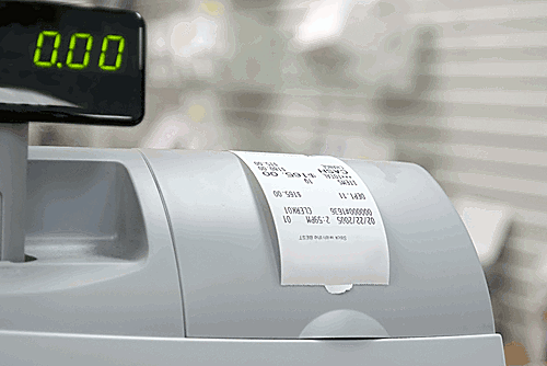 Close-up of a cash register with a digital display showing '0.00' and a printed receipt.