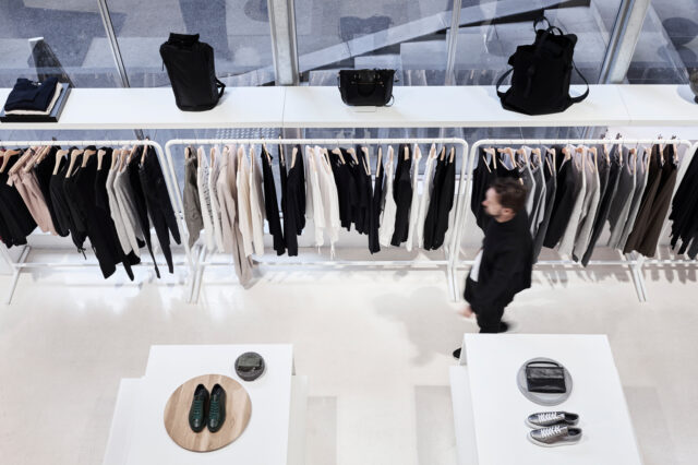 Interior of Swensk store with clothing racks, display tables, and a person walking through.