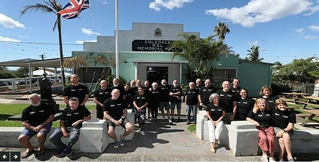 Group of Coledale RSL volunteers in black shirts posing in front of Coledale Memorial Hall.