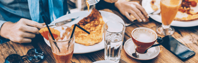 People eating a cafe breakfast. Close up of their hands and their plates full of food.