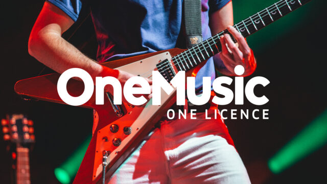 OneMusic logo overlay on a close up photo of a person playing a "Flying V" red guitar